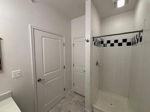 A white bathroom with a checkered shower curtain.