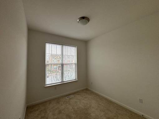 A room with a window showing a view of a building outside.