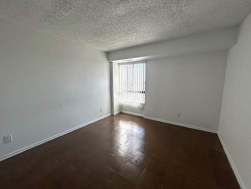 A room with a window and wooden flooring.