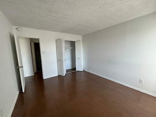 A room with white walls and wood flooring with two doors.
