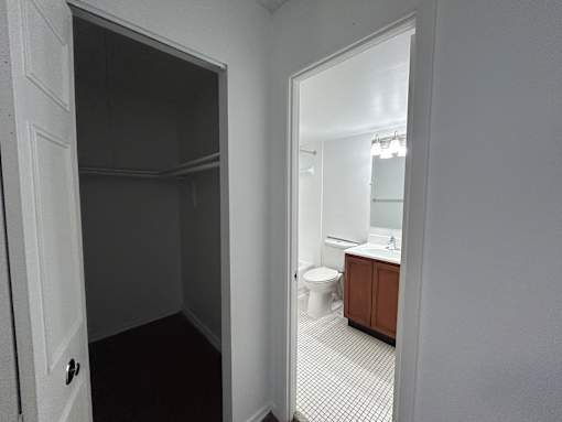 A bathroom with a toilet, sink, and a mirror is visible through an open door.