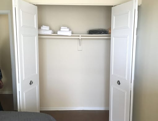 A white closet with a shelf and towels on it.