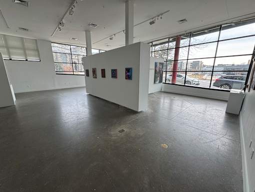A spacious room with a white wall and a large window.