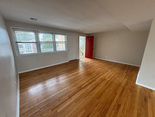 A room with wooden flooring and a red door.