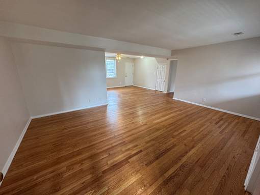 A room with wooden flooring and white walls.