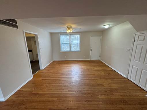 A room with wooden flooring and a window with blinds.