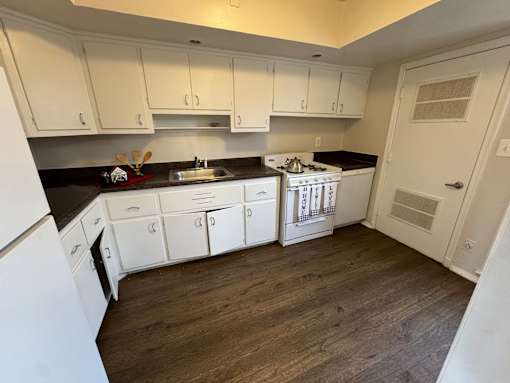 A kitchen with white cabinets and a black countertop.