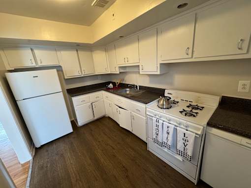 A kitchen with white appliances and cabinets.