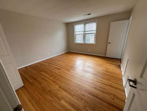A room with wooden flooring and a window.