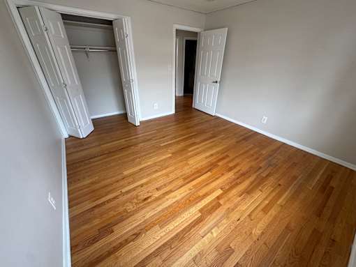 A room with wooden flooring and white walls.