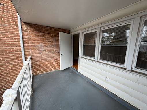 A balcony with a brick wall and a white door.