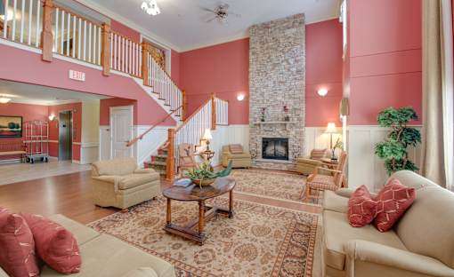 A living room with a stone fireplace and a staircase.