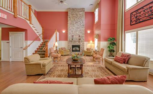 A living room with a stone fireplace and a staircase.