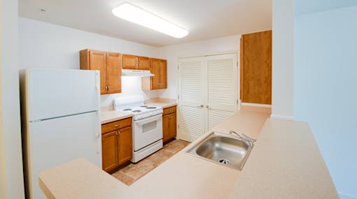 A kitchen with a white refrigerator, wooden cabinets, and a white stove top oven.