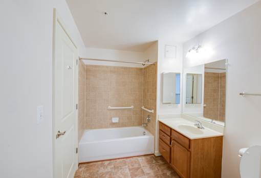 A bathroom with a tub, sink, and mirror.