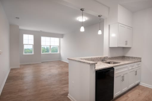 an empty kitchen and living room with white cabinets and granite counter tops