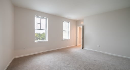 an empty living room with two windows and a door