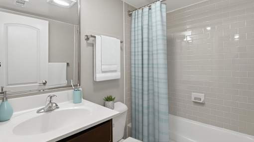 A white bathroom with a blue vase on the sink.