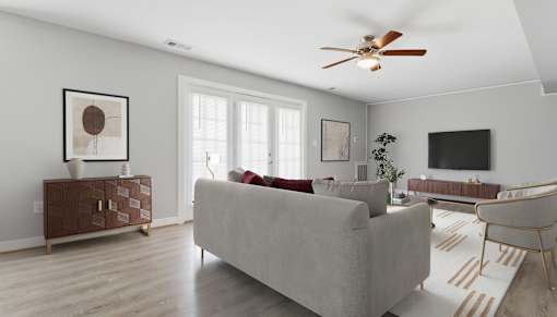 A living room with a grey couch, a brown side table, and a ceiling fan.