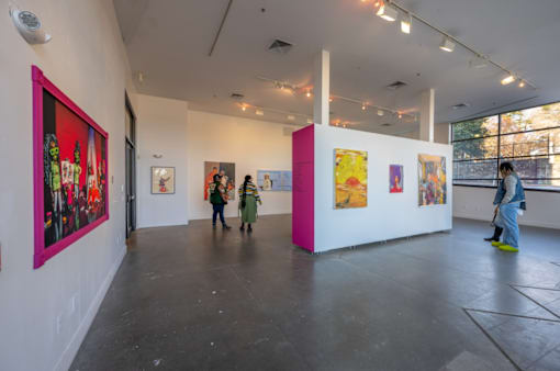 A group of people are looking at paintings in a gallery.