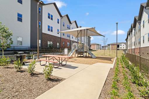 Community playground featuring a shaded play structure, picnic seating, and outdoor recreation space for residents and families.