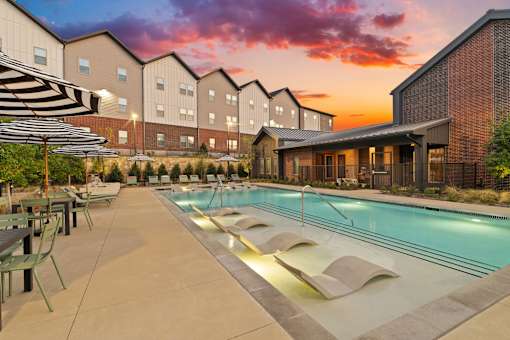 Resort-style swimming pool featuring in-water lounge seating, sun deck areas, and outdoor gathering space for residents.