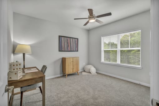 a bedroom with a desk and a ceiling fan