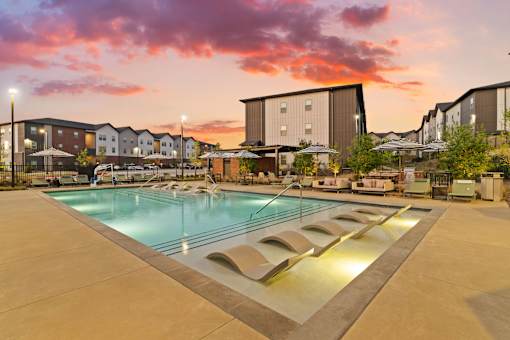 Resort-style swimming pool featuring in-water lounge seating, sun deck areas, and outdoor gathering space for residents.