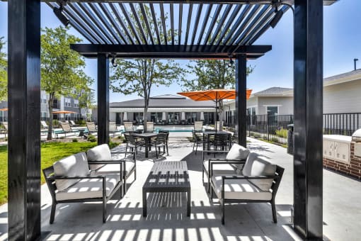 a patio with chairs and tables and a pool in the background