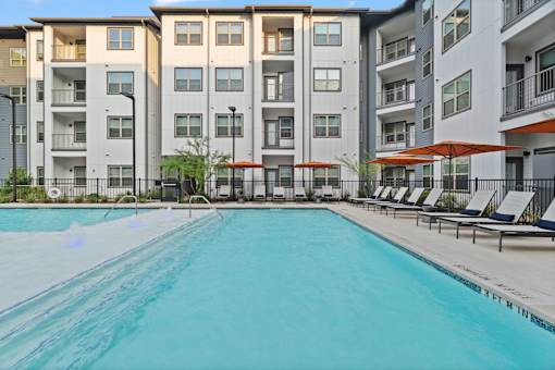 Apartment community pool featuring resort-style amenities, contemporary residential architecture, private balconies, and landscaped outdoor gathering spaces.