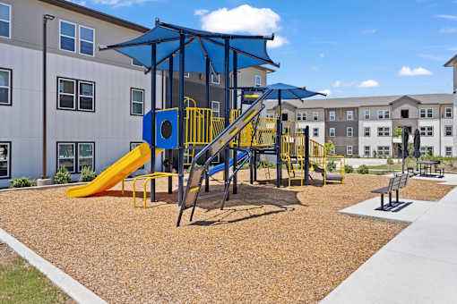 Outdoor playground at The Esther with slides, climbing structures and seating.