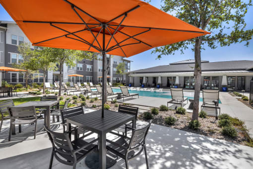 a patio with chairs and tables and a pool in the background