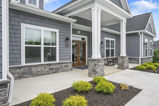 the front porch of a gray house with a concrete walkway