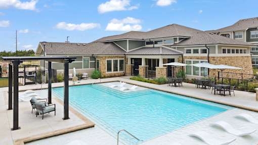 A large outdoor swimming pool with lounge chairs and a pergola.