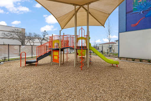 A playground with a yellow slide and orange and green play structures.
