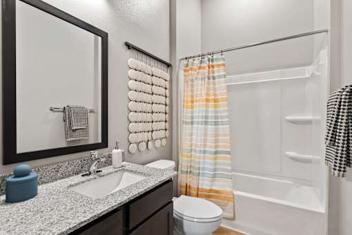 Full bathroom featuring a tub-shower combination, granite-style vanity countertop, and contemporary finishes.
