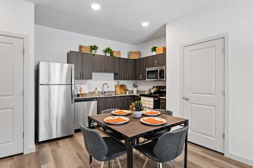 Modern apartment kitchen at The Esther with stainless steel appliances and dark wood cabinetry.