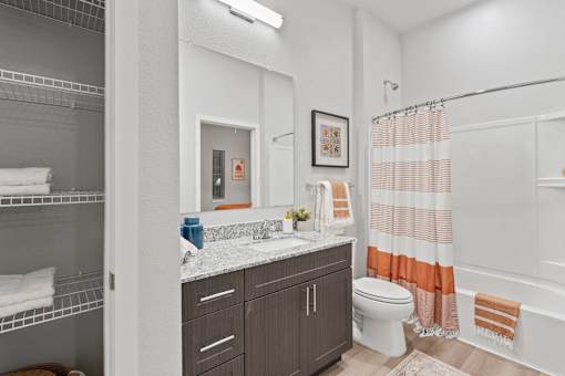 Residential apartment bathroom featuring contemporary finishes, a spacious vanity, integrated storage, and functional everyday living accommodations.