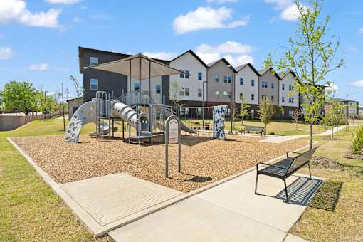 Community playground featuring shaded play equipment, climbing structures, and outdoor recreation space for children and families.