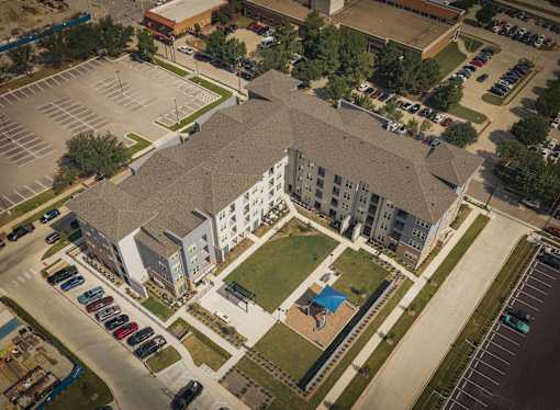 An aerial view of a parking lot and a building with a green lawn in front.