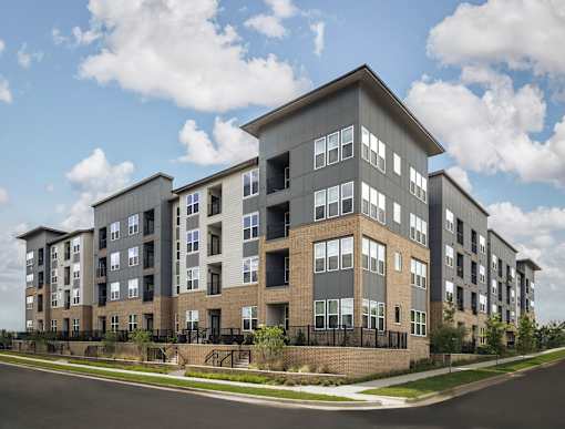 A modern apartment building with a mix of grey and brown exterior walls.