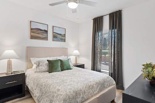 Bedroom at The Esther apartments with bed, dresser and nightstands in an open floor plan layout.