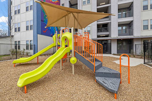 A playground with a yellow slide and orange railings.