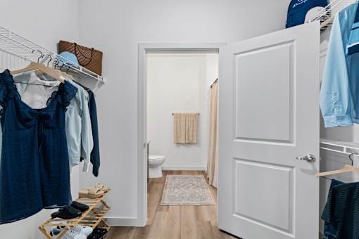 Organized walk-in closet with hanging clothes, shelves, and storage space at The Esther apartments in Converse, TX.