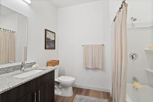 Modern bathroom at Aviator 1518 with dark wood vanity, mirror, toilet and shower.