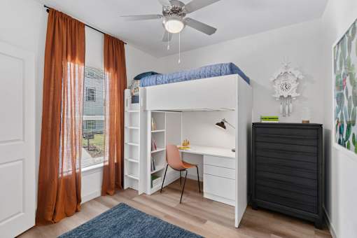 Bedroom at The Esther apartments with bunkbed desk combo, dresser and ceiling fan.