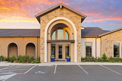 A building with a large arched entrance and a parking lot in front.
