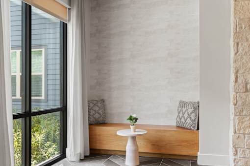 Integrated resident lounge nook featuring custom built-in bench seating, natural wood finishes, floor-to-ceiling windows, and a quiet retreat for work, reading, or casual gathering.
