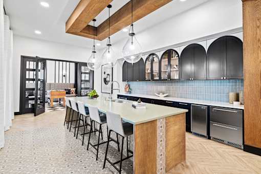 a large kitchen with a long island with chairs and blue tiles
