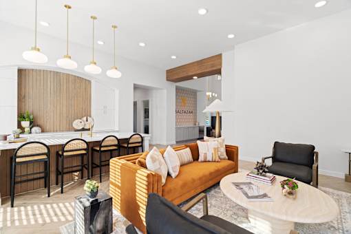 a living room with an orange couch and a kitchen with a table and chairs